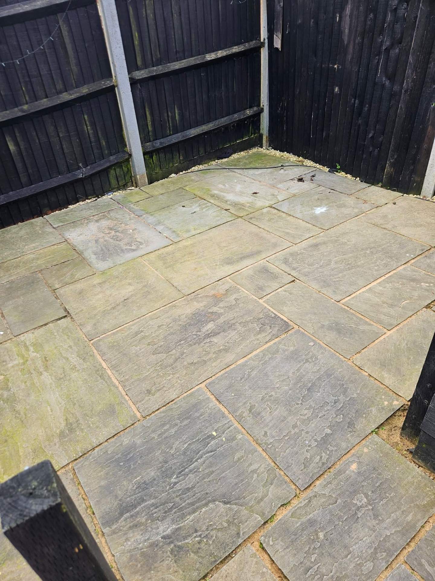 Beige sandstone patio with orange staining and dirt build-up before pressure washing