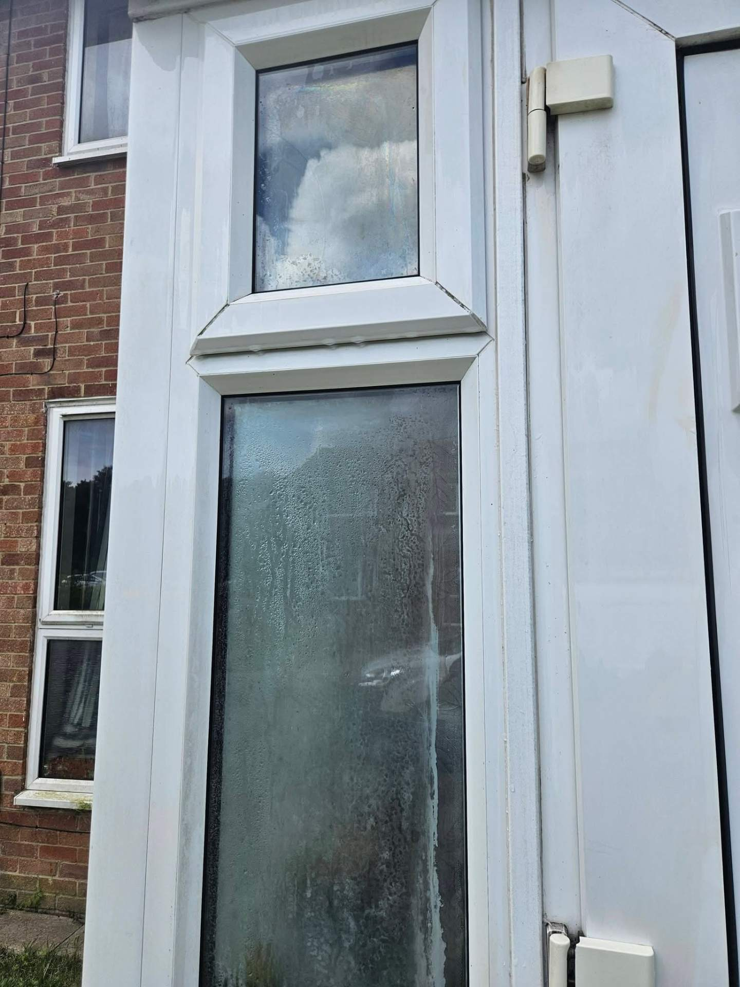 Weather-stained white UPVC front door and side panel with grimy glass and frames — before soft UPVC clean