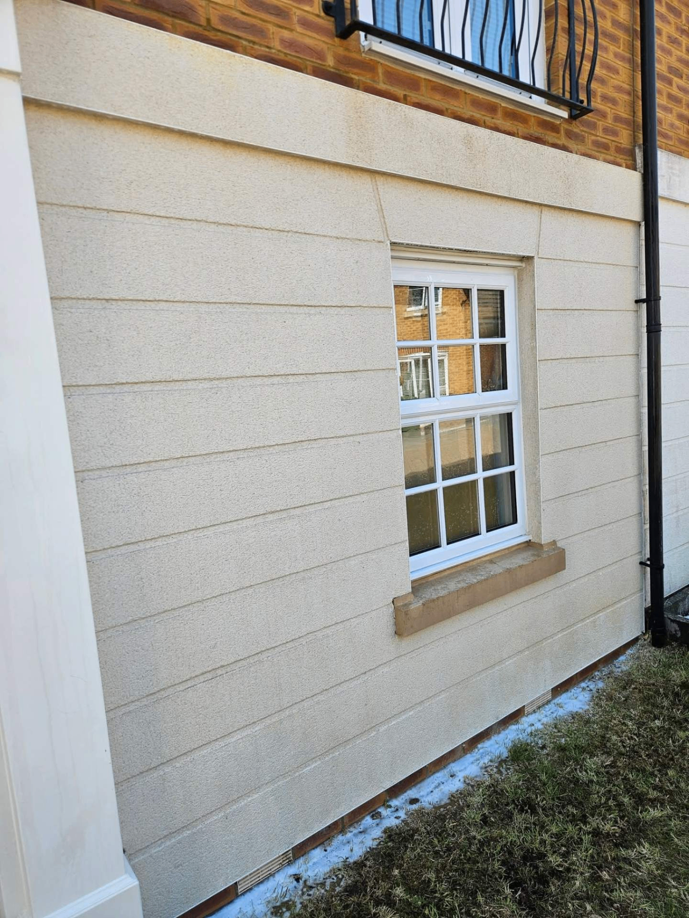 Freshly softwashed cream render around a UPVC sash window — biocide-cleaned finish in South Hampshire